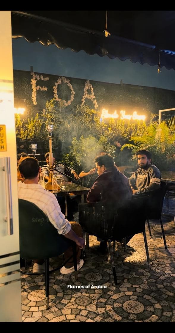 Hookah table and guests on the Flames rooftop at night